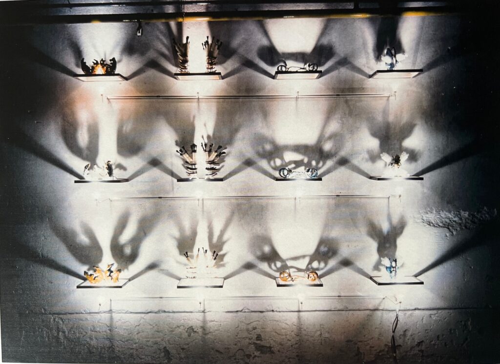 small sculpture on a wall with light underneath by marcella van zanten